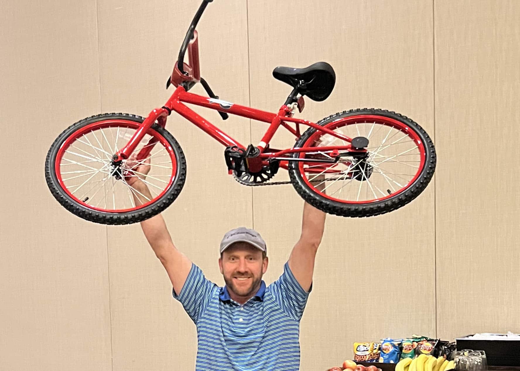 Man carrying a bicycle over his head during a Build-A-Bike charity event.